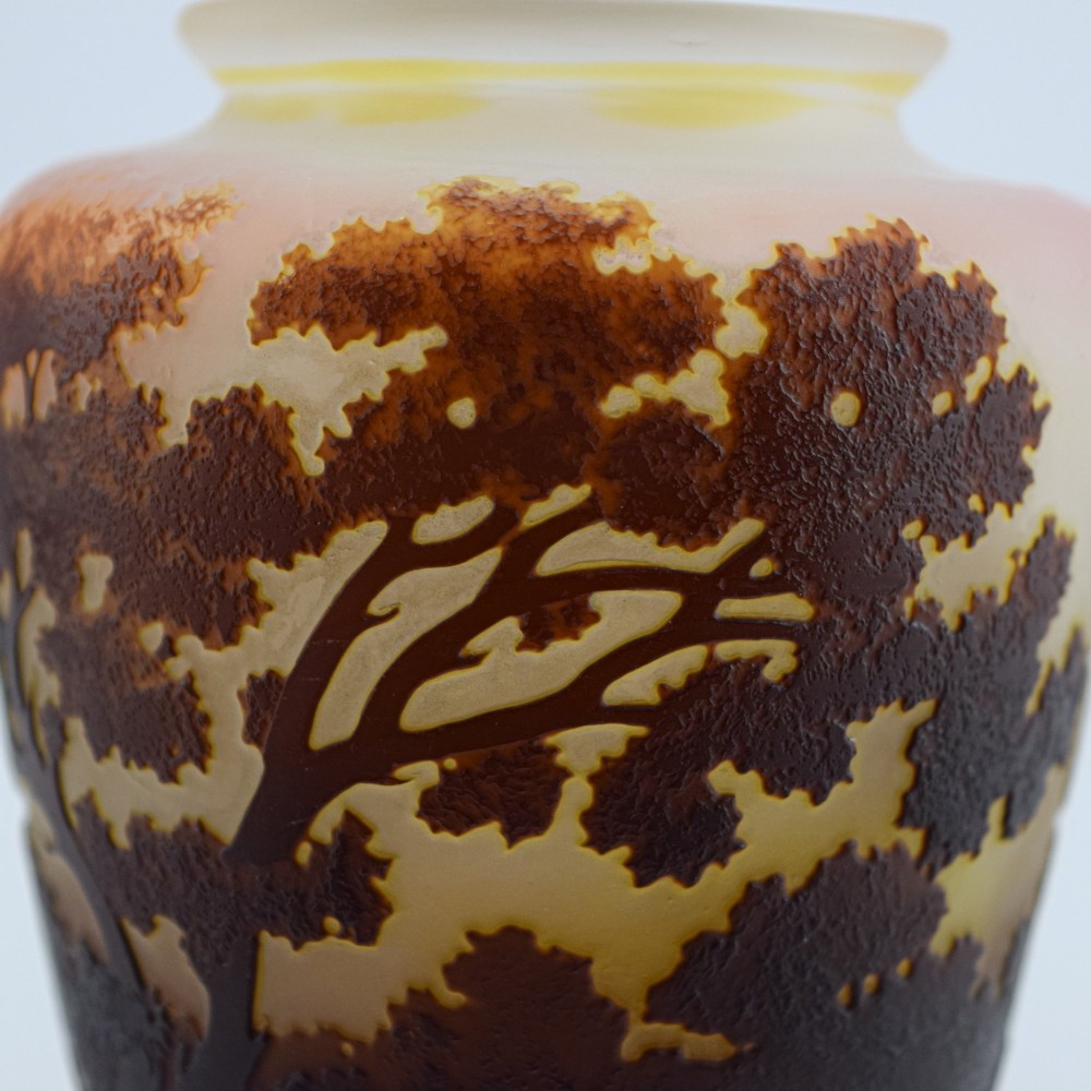 An Art Nouveau cameo glass vase featuring an acid-etched dark brown woodland landscape set against a warm yellow and soft pink background. View X
