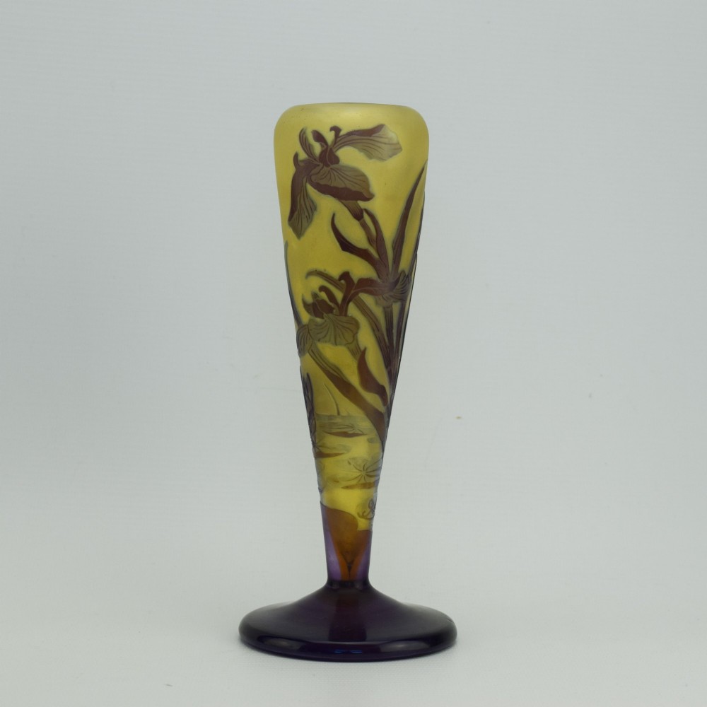 An Art Nouveau cameo glass vase featuring dark purple and brown acid-etched iris flowers against a textured yellow background with a dark purple foot.