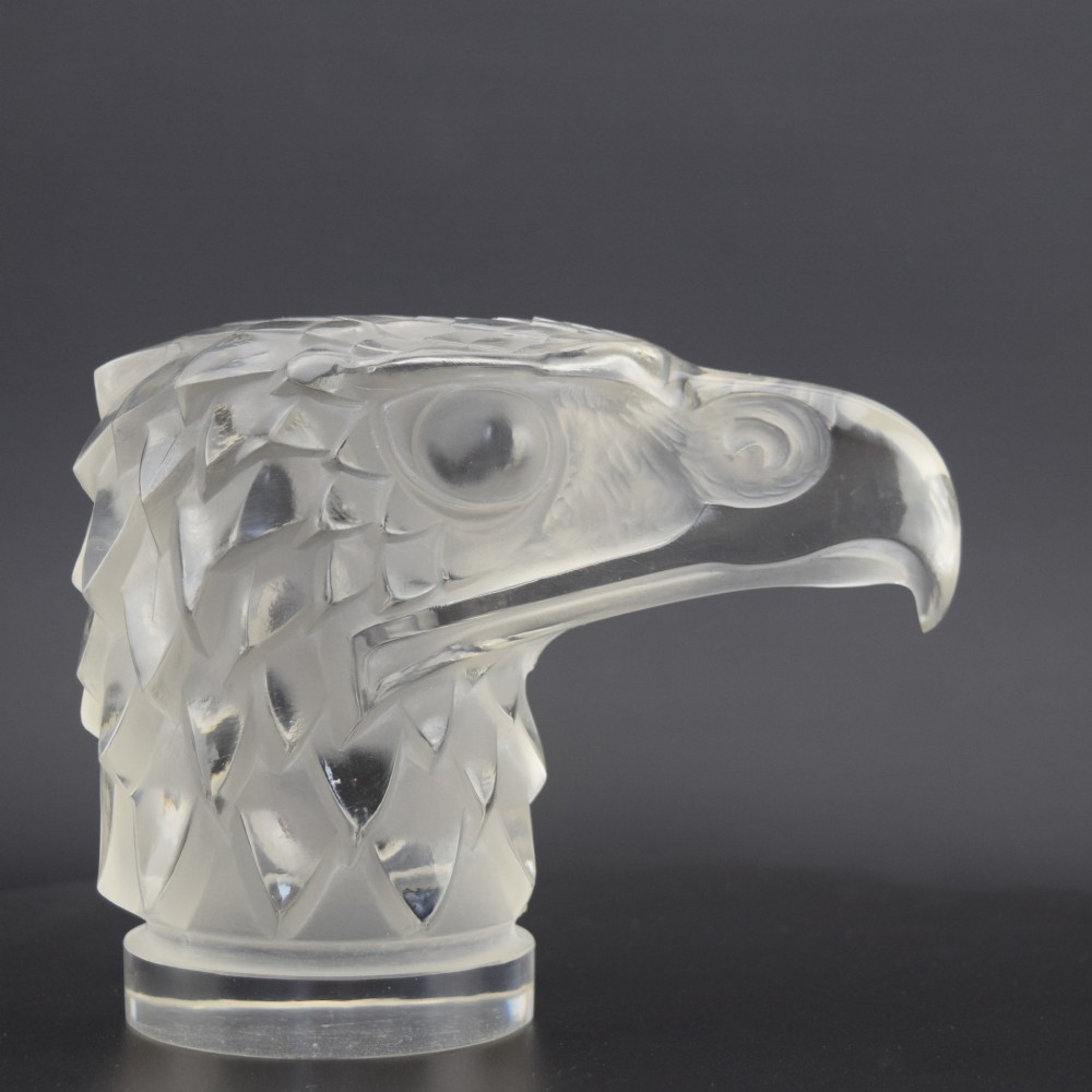 A clear and frosted moulded glass sculpture depicting an eagle head in profile, designed as an Art Deco automobile mascot.