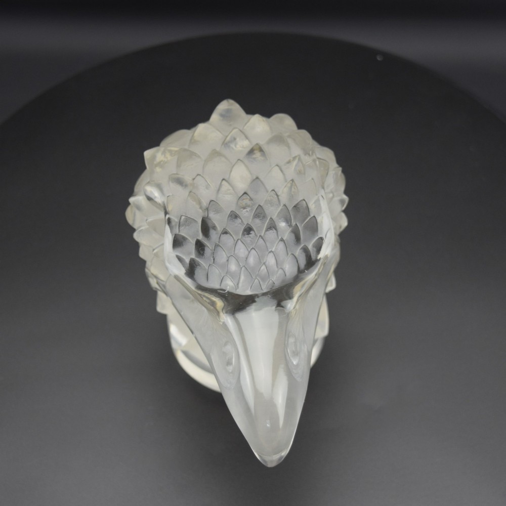 A clear and frosted moulded glass sculpture depicting an eagle head in profile, designed as an Art Deco automobile mascot. View VII