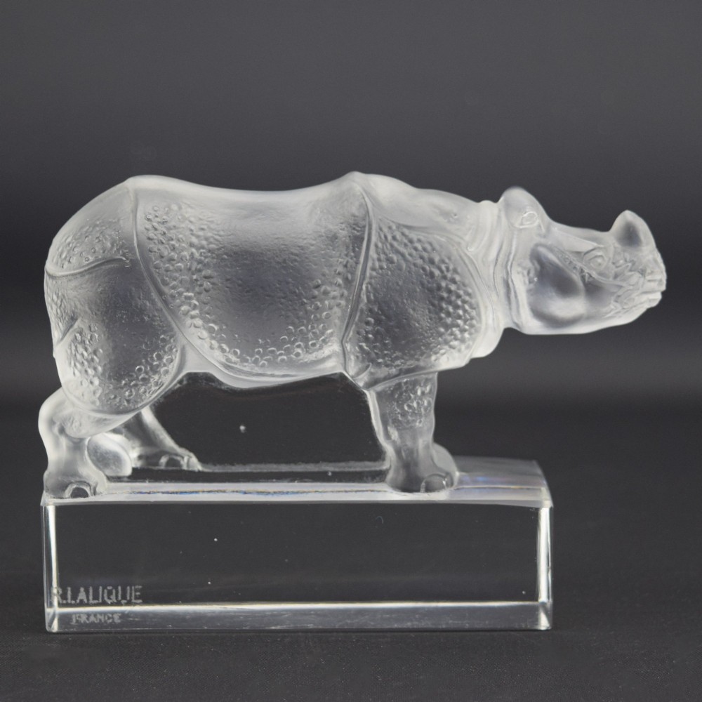 A moulded clear and frosted glass paperweight featuring a stylized rhinoceros standing on an integral rectangular base, marked R. Lalique France.