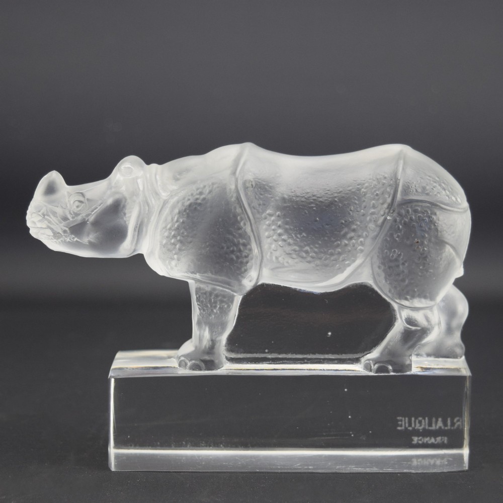 A moulded clear and frosted glass paperweight featuring a stylized rhinoceros standing on an integral rectangular base, marked R. Lalique France. View II