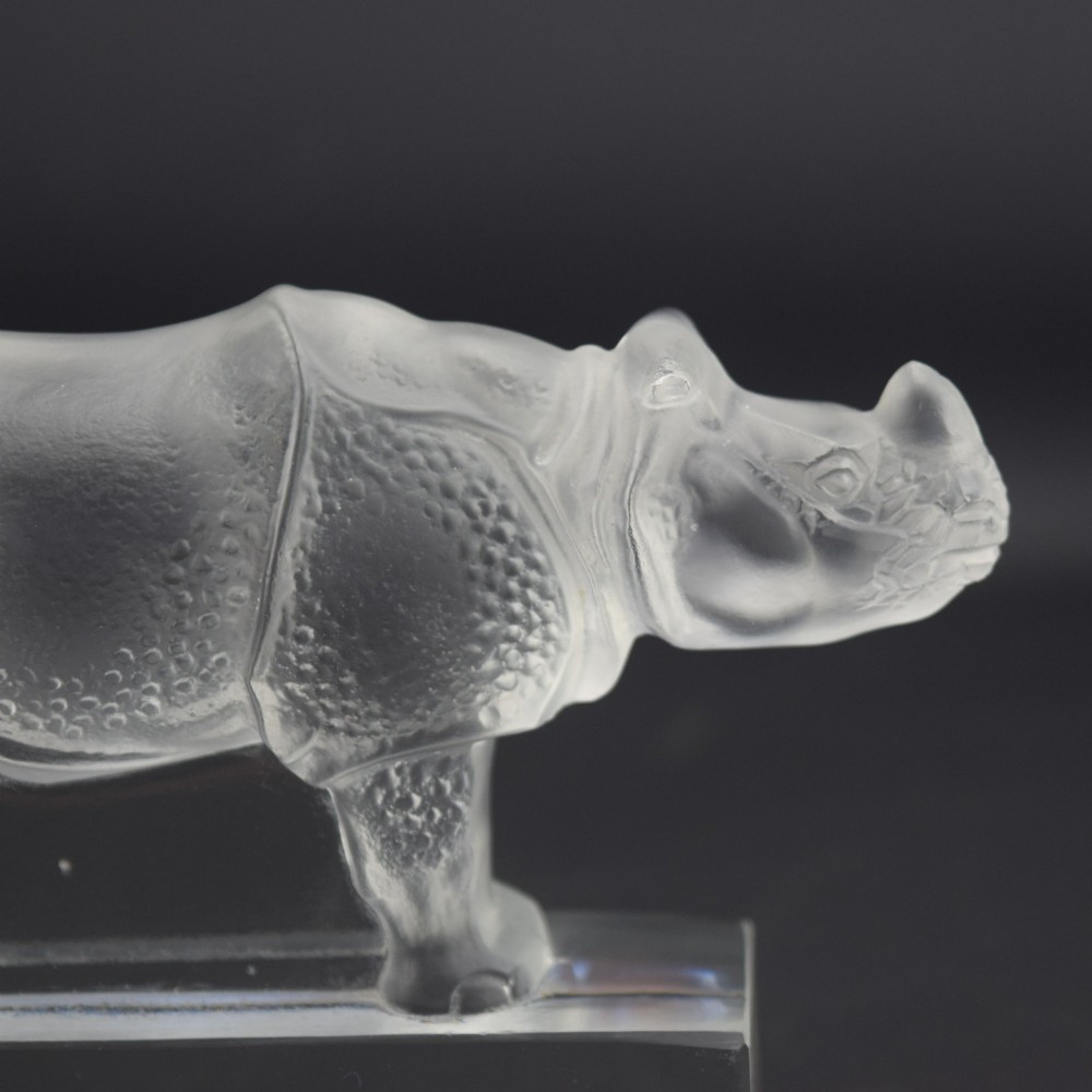 A moulded clear and frosted glass paperweight featuring a stylized rhinoceros standing on an integral rectangular base, marked R. Lalique France. View V