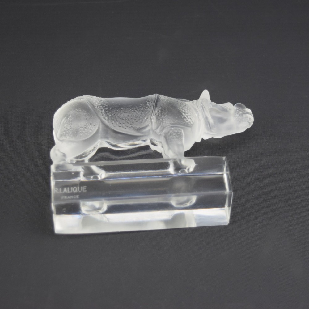 A moulded clear and frosted glass paperweight featuring a stylized rhinoceros standing on an integral rectangular base, marked R. Lalique France. View VIII