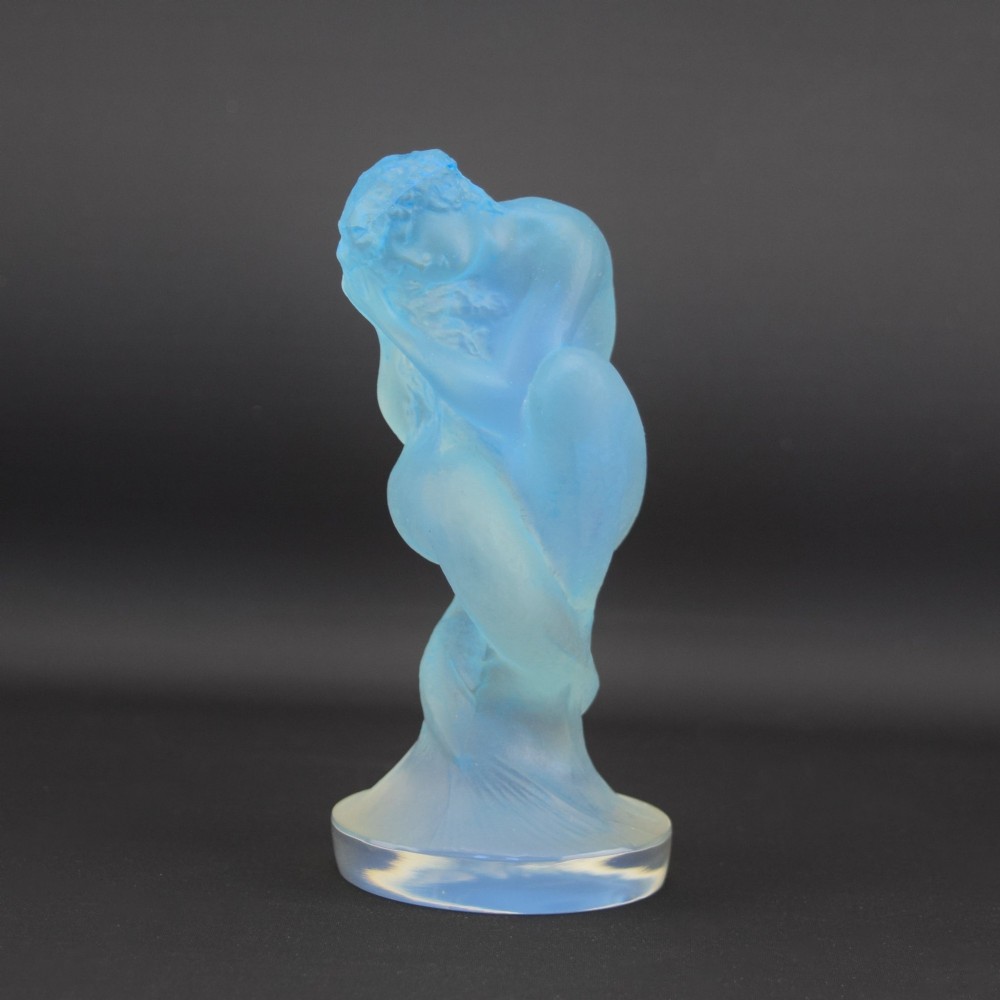 An Art Deco opalescent blue glass car mascot depicting a Sirene or mermaid-like crouching figure on a circular base.