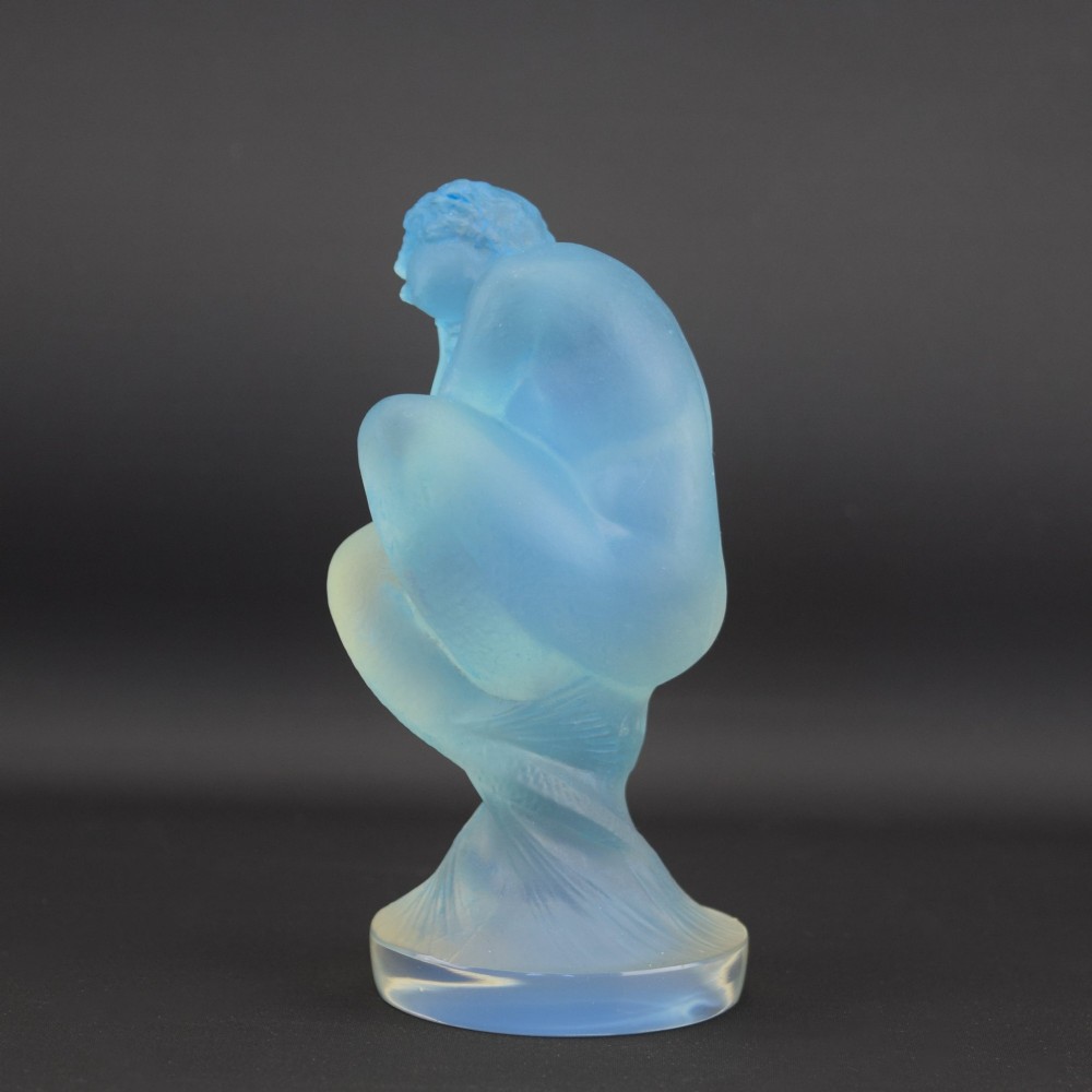 An Art Deco opalescent blue glass car mascot depicting a Sirene or mermaid-like crouching figure on a circular base. View II