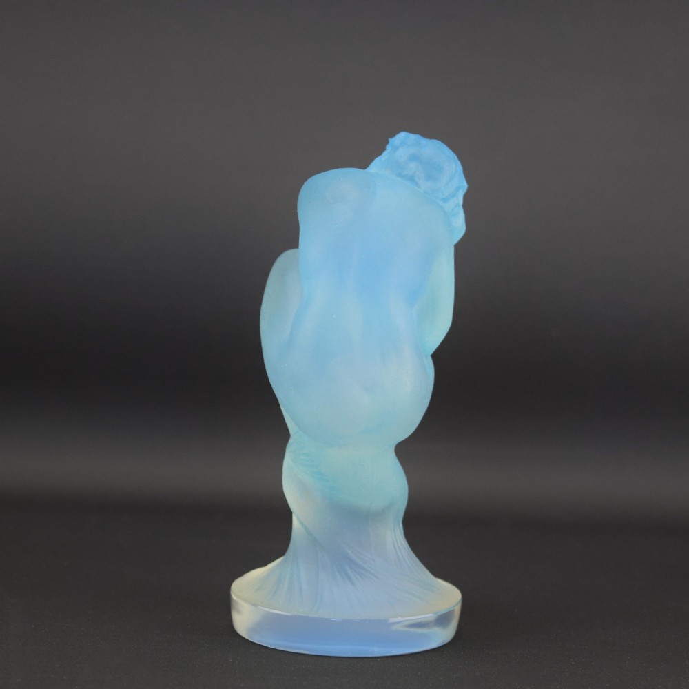 An Art Deco opalescent blue glass car mascot depicting a Sirene or mermaid-like crouching figure on a circular base. View III