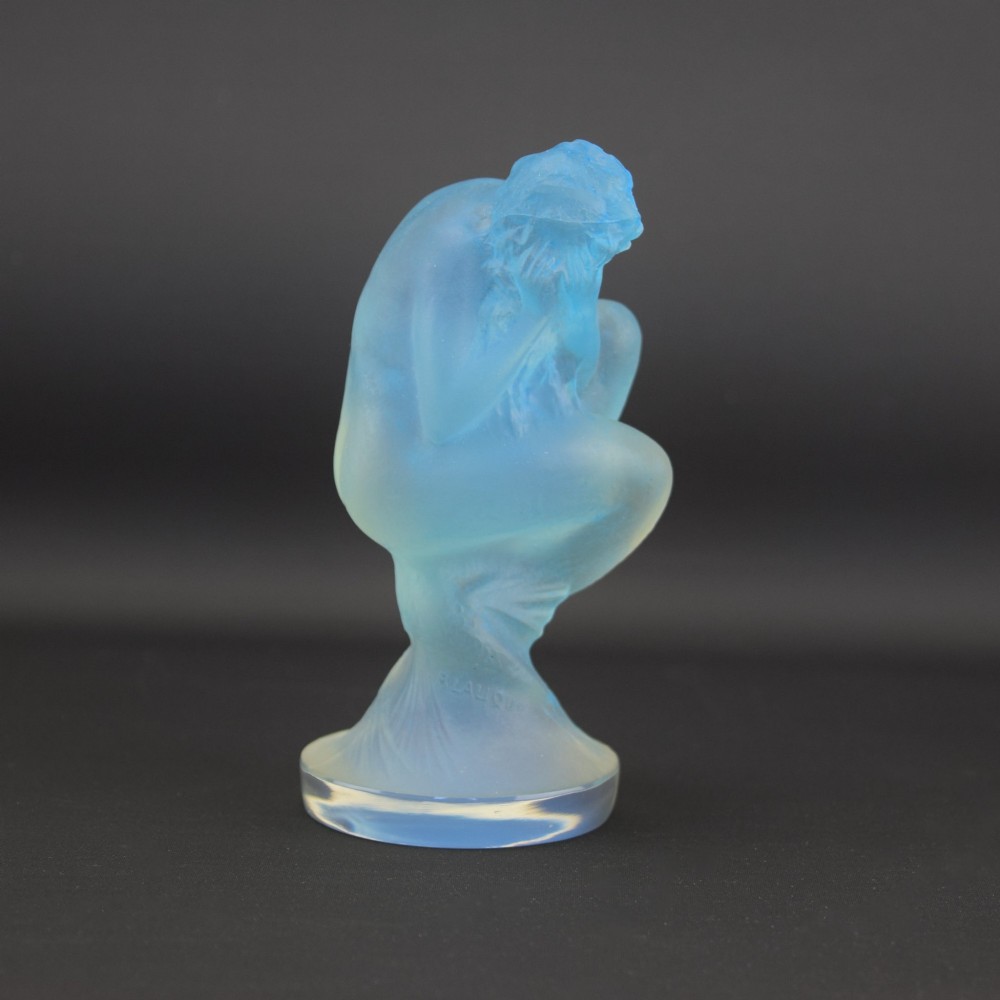 An Art Deco opalescent blue glass car mascot depicting a Sirene or mermaid-like crouching figure on a circular base. View V