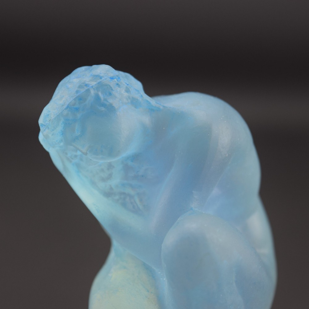 An Art Deco opalescent blue glass car mascot depicting a Sirene or mermaid-like crouching figure on a circular base. View VIII