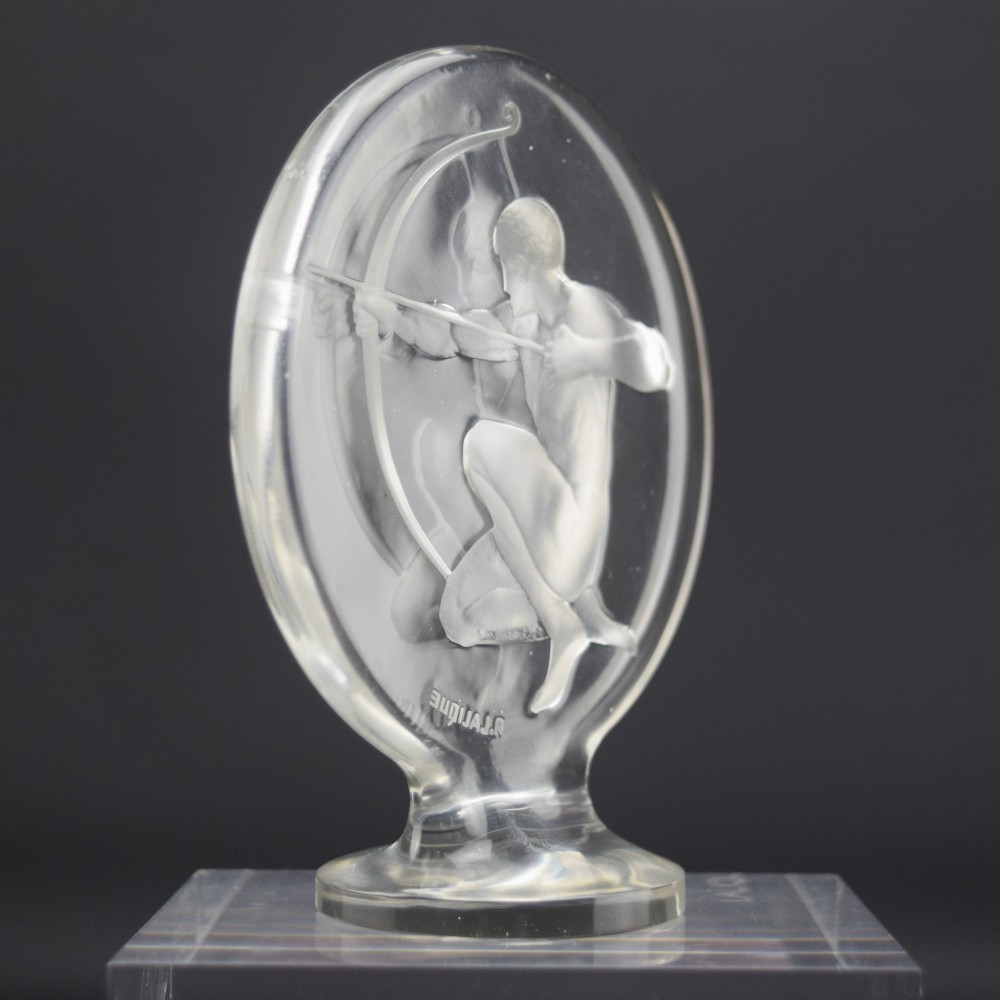 A circular clear and frosted Art Deco glass car mascot by Rene Lalique featuring a relief carving of a kneeling archer drawing a bow. View III