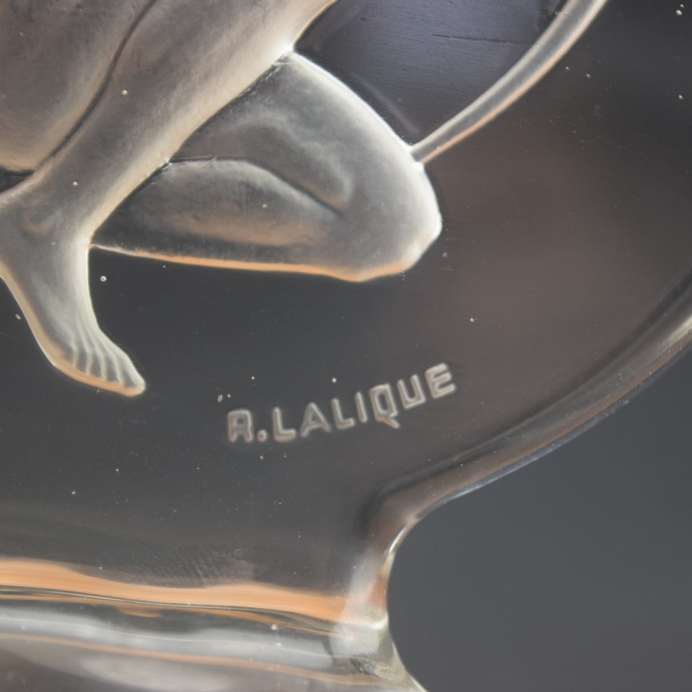 A circular clear and frosted Art Deco glass car mascot by Rene Lalique featuring a relief carving of a kneeling archer drawing a bow. View V