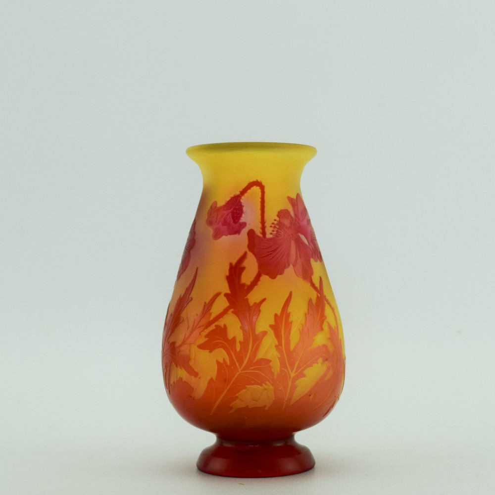 An Art Nouveau French cameo glass footed vase featuring an acid-etched red poppy design over a translucent yellow and orange ground.
