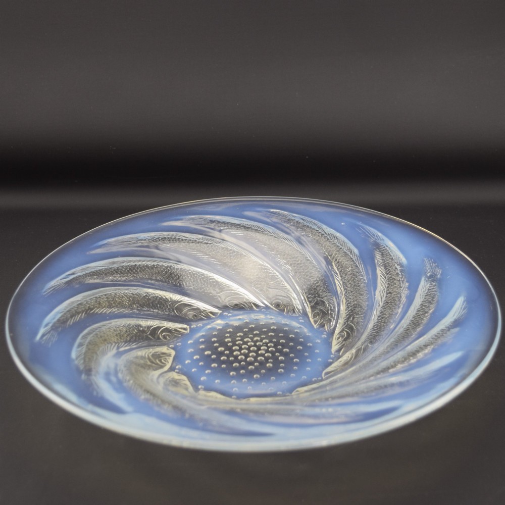 A circular Art Deco opalescent blue glass shallow bowl decorated with a spiralling pattern of moulded fish and a central field of small raised bubbles. View II