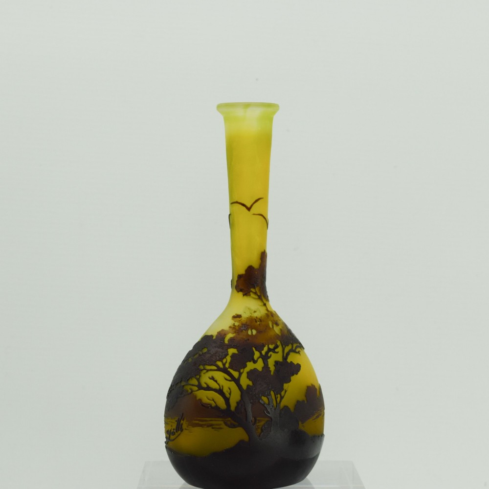 A yellow and dark brown Art Nouveau cameo glass vase featuring an acid-etched forest landscape with trees and birds on a long slender neck. View II