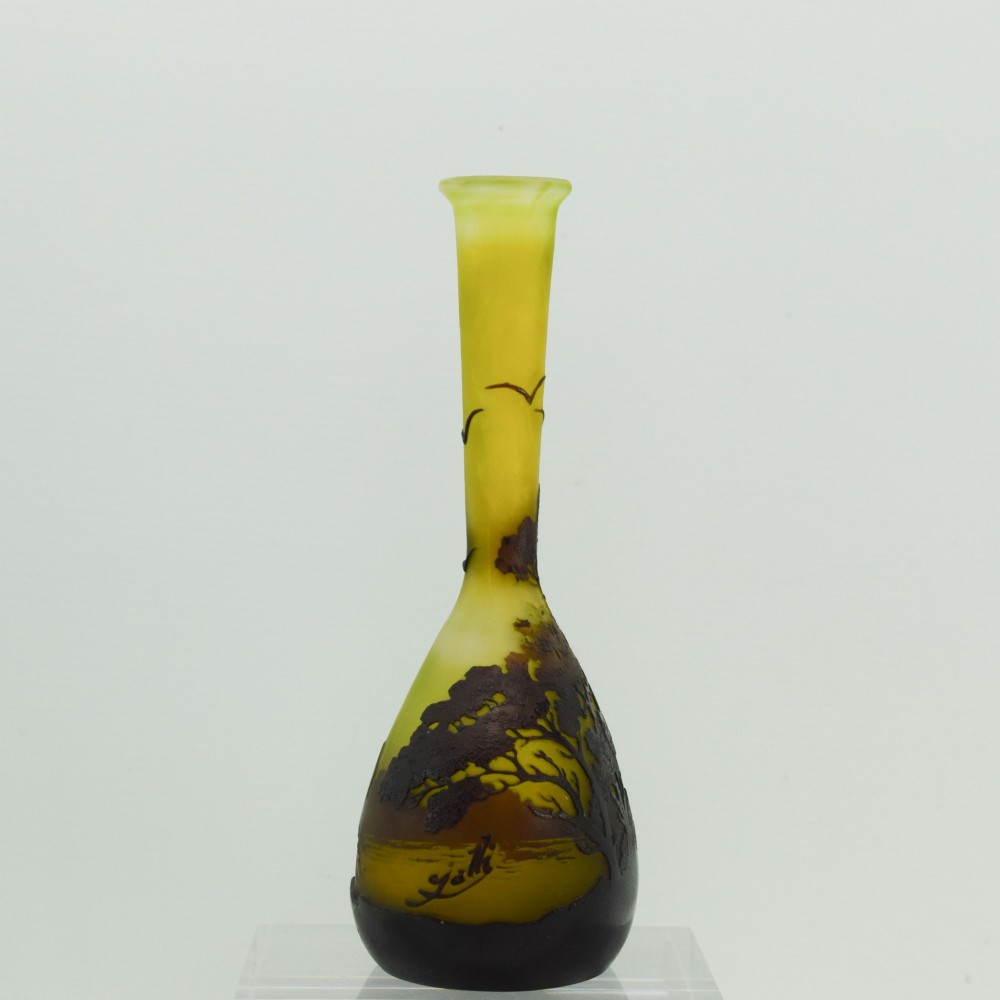 A yellow and dark brown Art Nouveau cameo glass vase featuring an acid-etched forest landscape with trees and birds on a long slender neck. View III