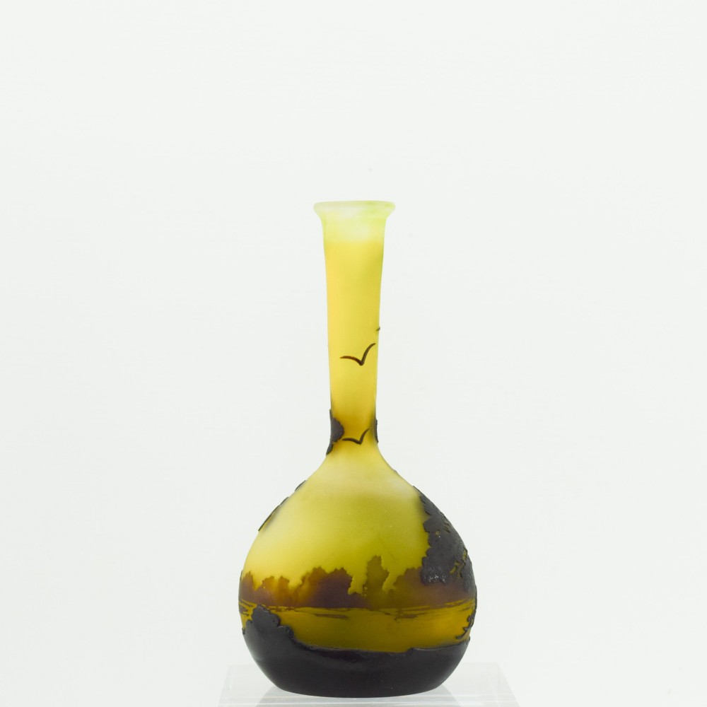 A yellow and dark brown Art Nouveau cameo glass vase featuring an acid-etched forest landscape with trees and birds on a long slender neck. View IV