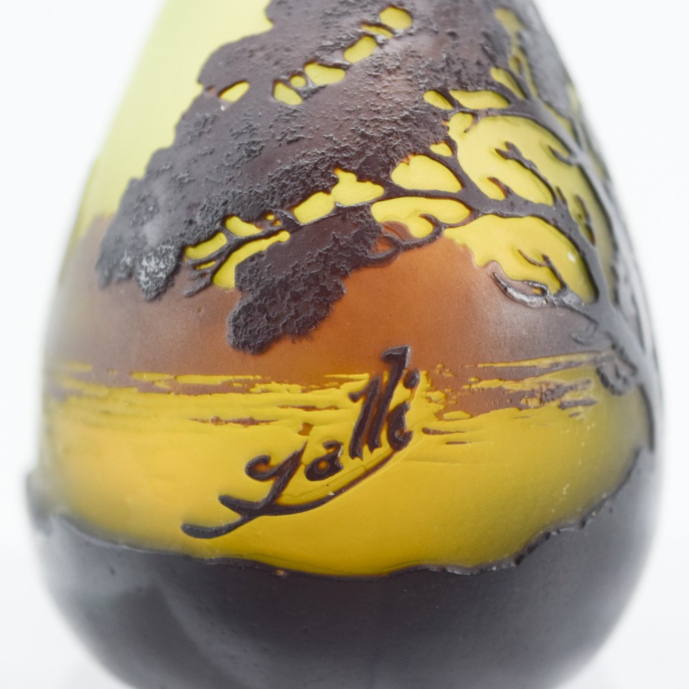 A yellow and dark brown Art Nouveau cameo glass vase featuring an acid-etched forest landscape with trees and birds on a long slender neck. View VIII