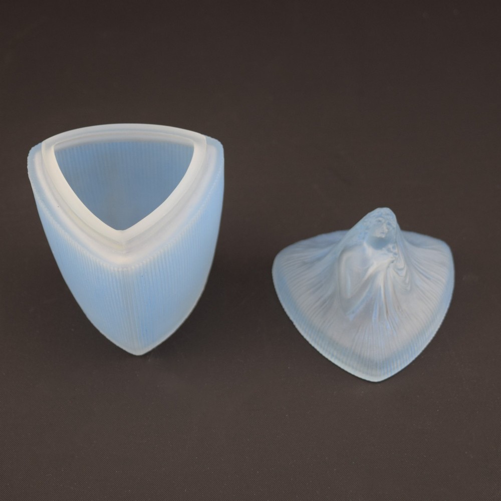 An opalescent blue glass powder box designed by Rene Lalique featuring a moulded female head with flowing drapery on the lid and vertical ribbed sides. View VI