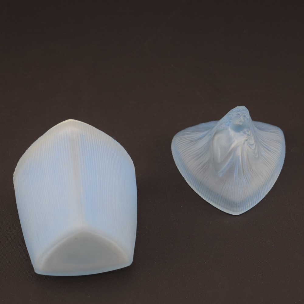 An opalescent blue glass powder box designed by Rene Lalique featuring a moulded female head with flowing drapery on the lid and vertical ribbed sides. View VIII