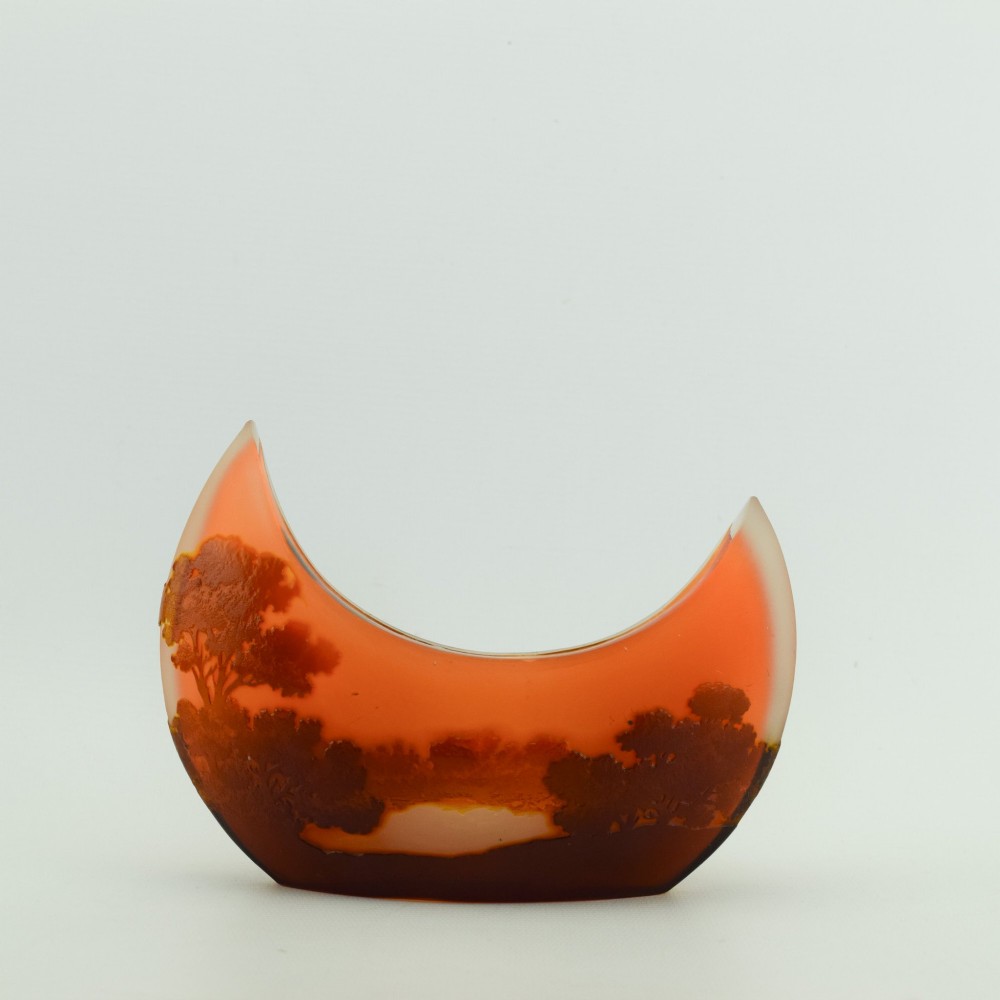 A crescent-shaped Art Nouveau cameo glass vase featuring an acid-etched river landscape in shades of burnt orange and dark brown against a frosted background. View V