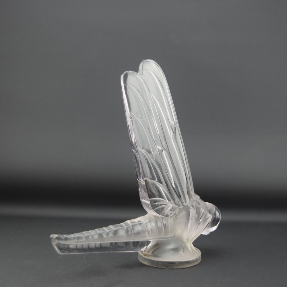 An Art Deco clear and frosted glass car mascot sculpted in the form of a stylised dragonfly with upright wings resting on a circular base. View VI