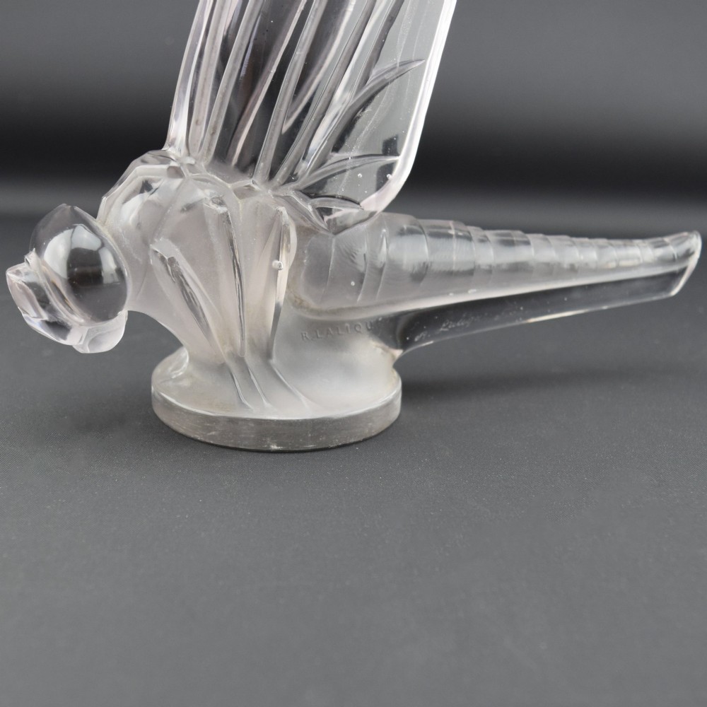 An Art Deco clear and frosted glass car mascot sculpted in the form of a stylised dragonfly with upright wings resting on a circular base. View VIII
