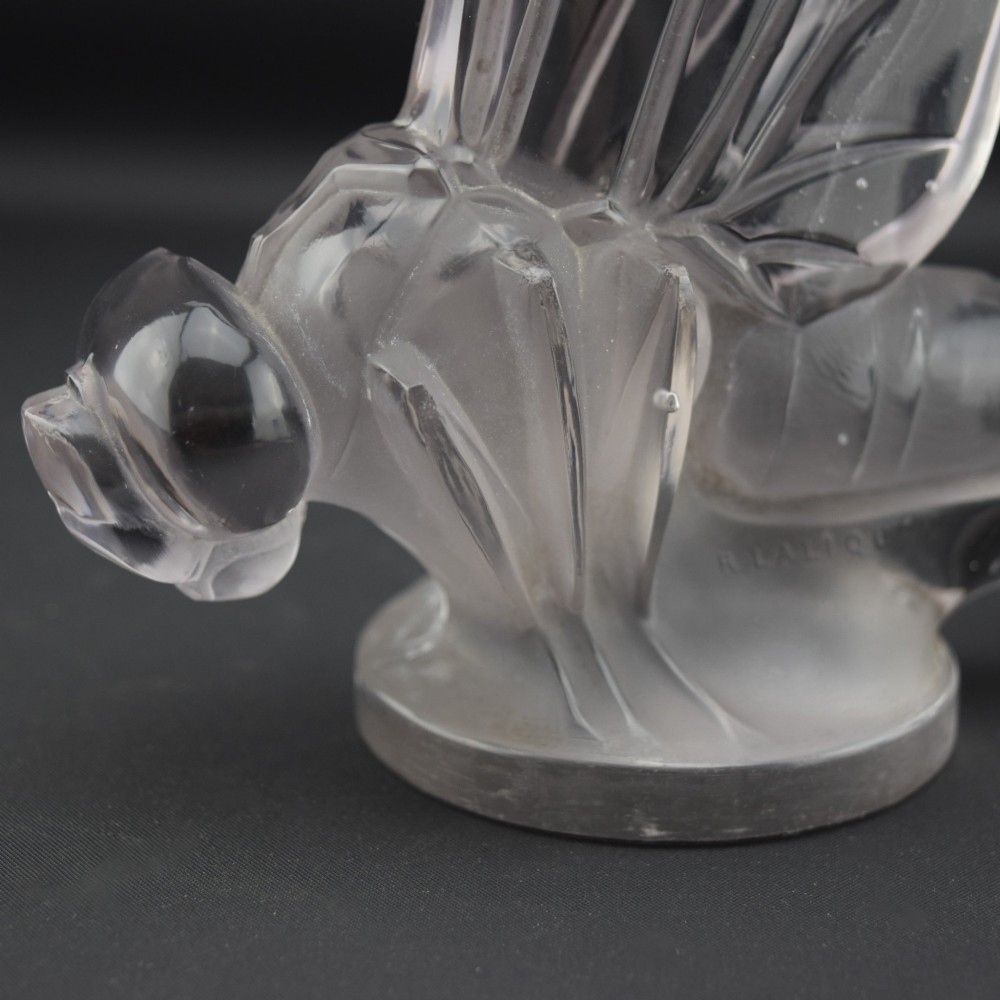 An Art Deco clear and frosted glass car mascot sculpted in the form of a stylised dragonfly with upright wings resting on a circular base. View IX
