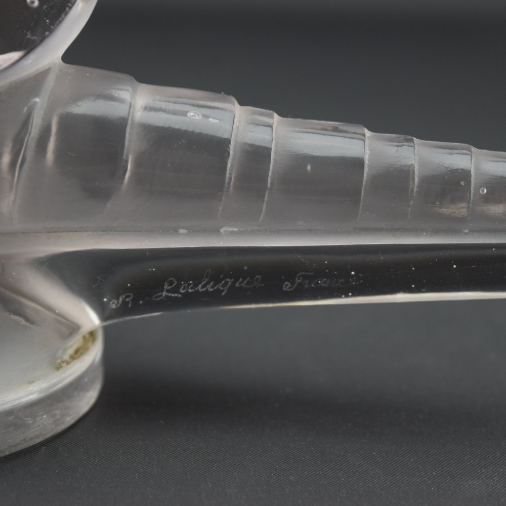 An Art Deco clear and frosted glass car mascot sculpted in the form of a stylised dragonfly with upright wings resting on a circular base. View X