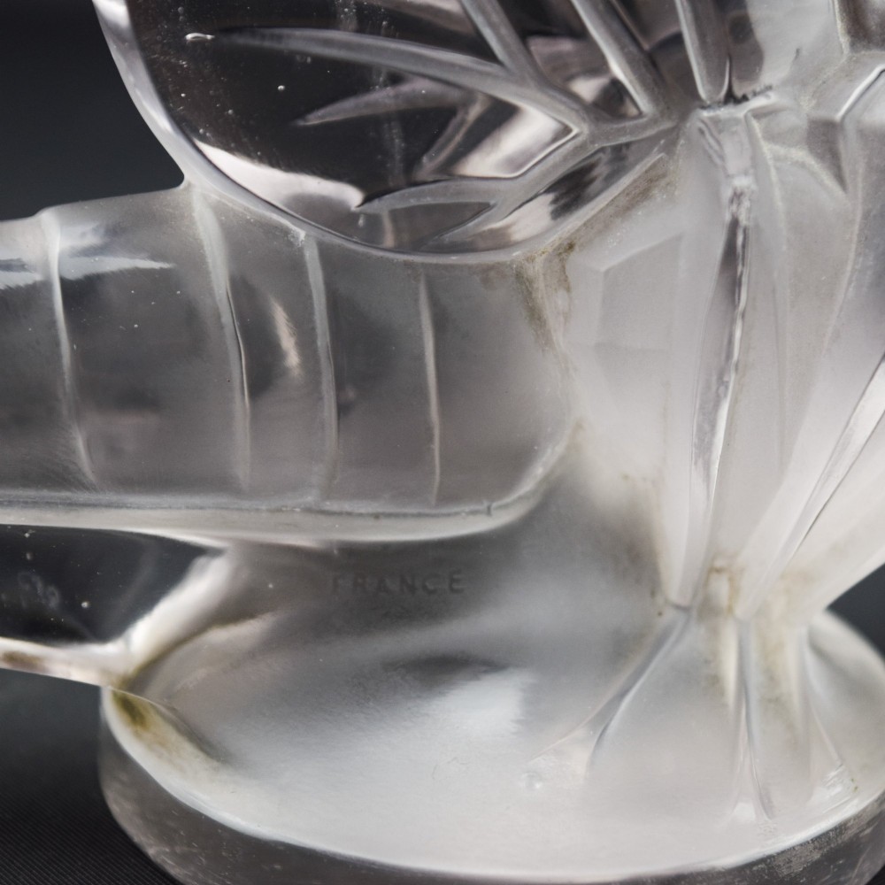 An Art Deco clear and frosted glass car mascot sculpted in the form of a stylised dragonfly with upright wings resting on a circular base. View XIII