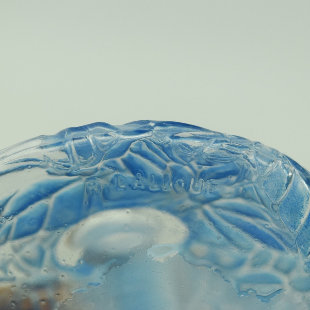 A circular Art Deco clear glass perfume bottle featuring relief butterfly motifs stained in blue with a matching circular glass stopper. View VIII