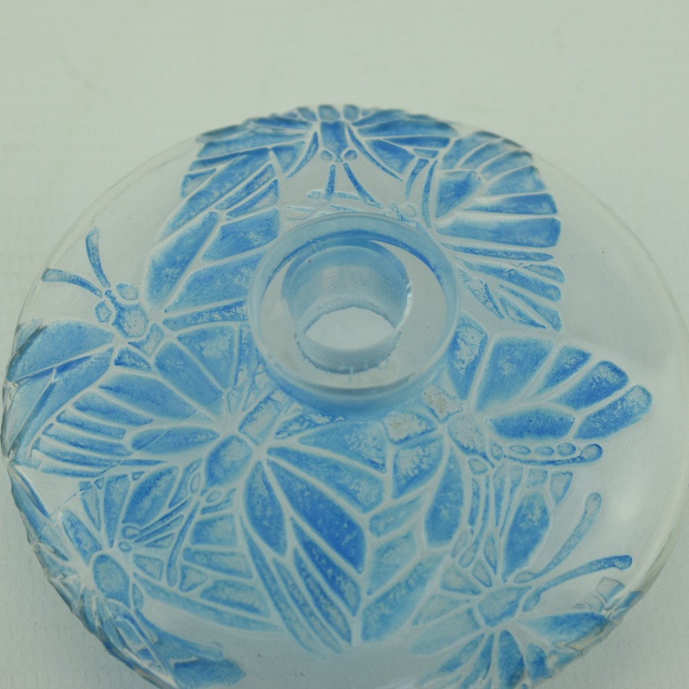 A circular Art Deco clear glass perfume bottle featuring relief butterfly motifs stained in blue with a matching circular glass stopper. View IX