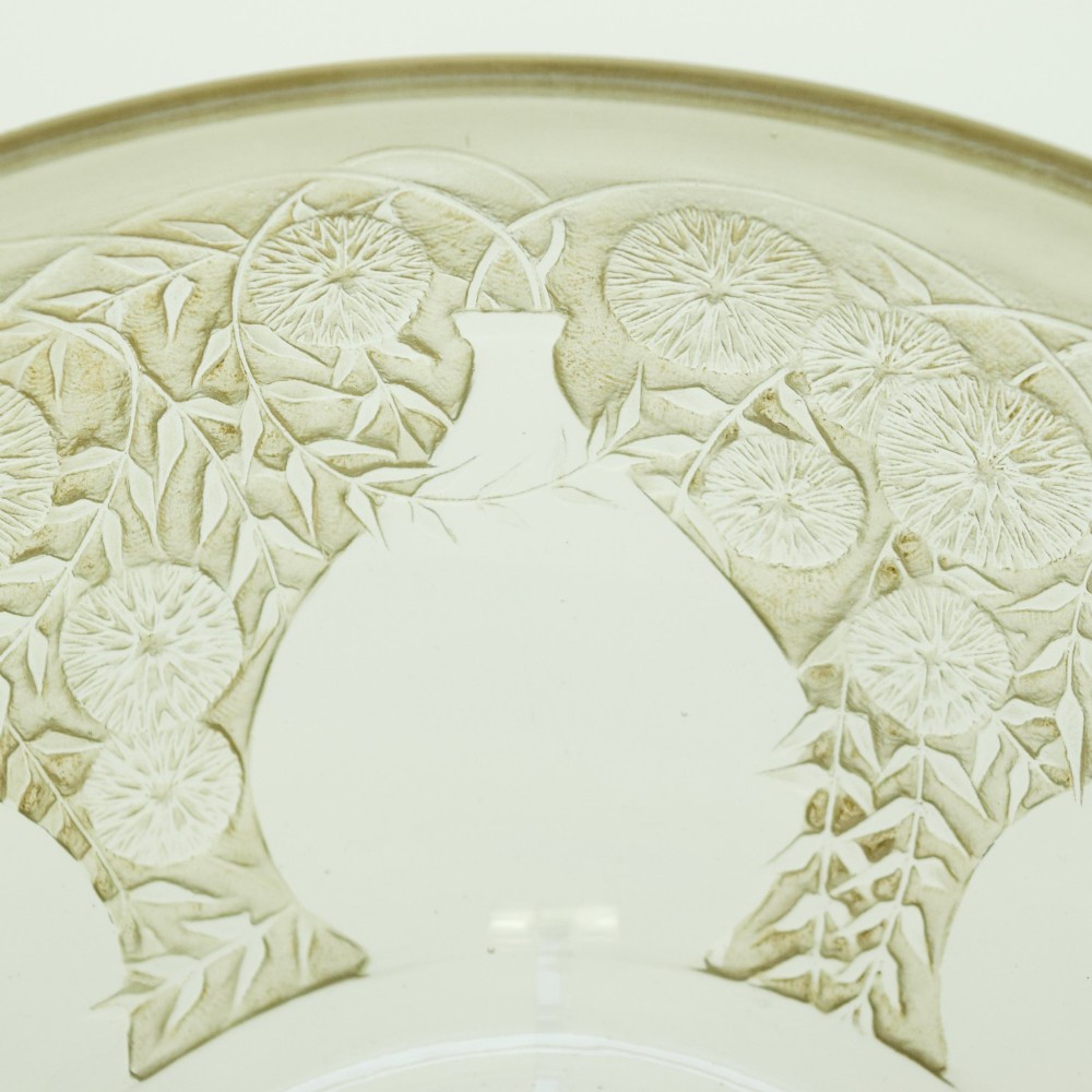 A circular clear glass shallow coupe bowl featuring frosted relief patterns of small vases and botanical motifs around a central medallion. View II