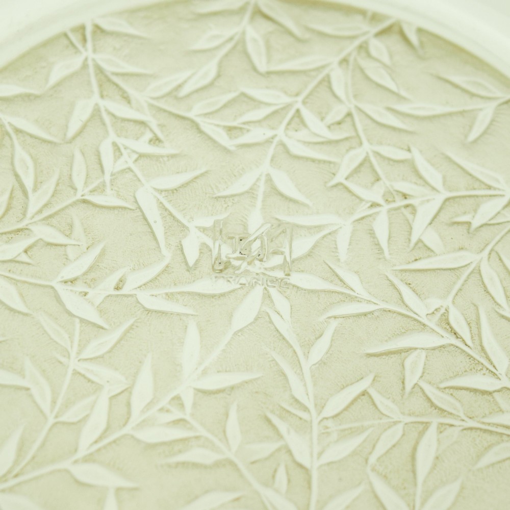 A circular clear glass shallow coupe bowl featuring frosted relief patterns of small vases and botanical motifs around a central medallion. View III