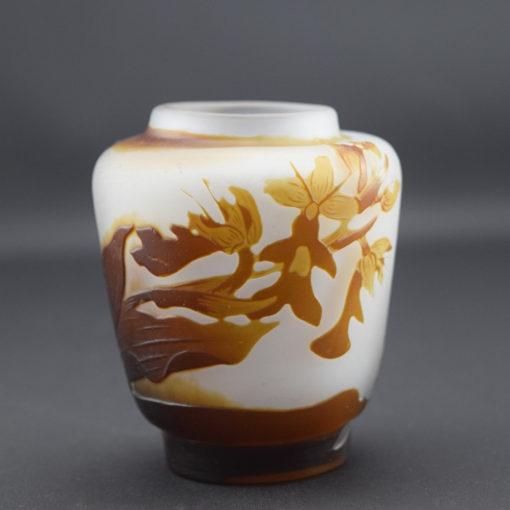 A small Art Nouveau cameo glass vase featuring brown acid-etched floral motifs over a frosted white background.
