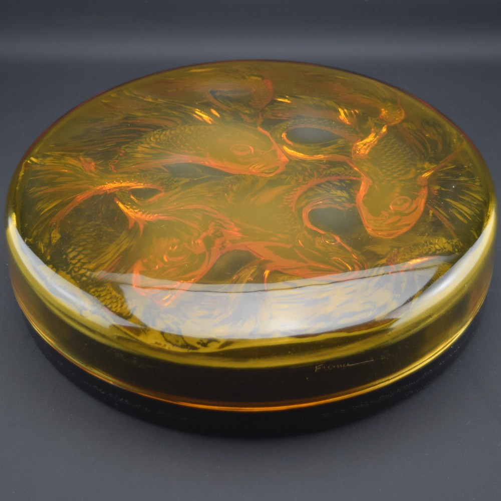 A circular amber opalescent glass box decorated with relief-moulded carp fish swirling in a central motif. View II