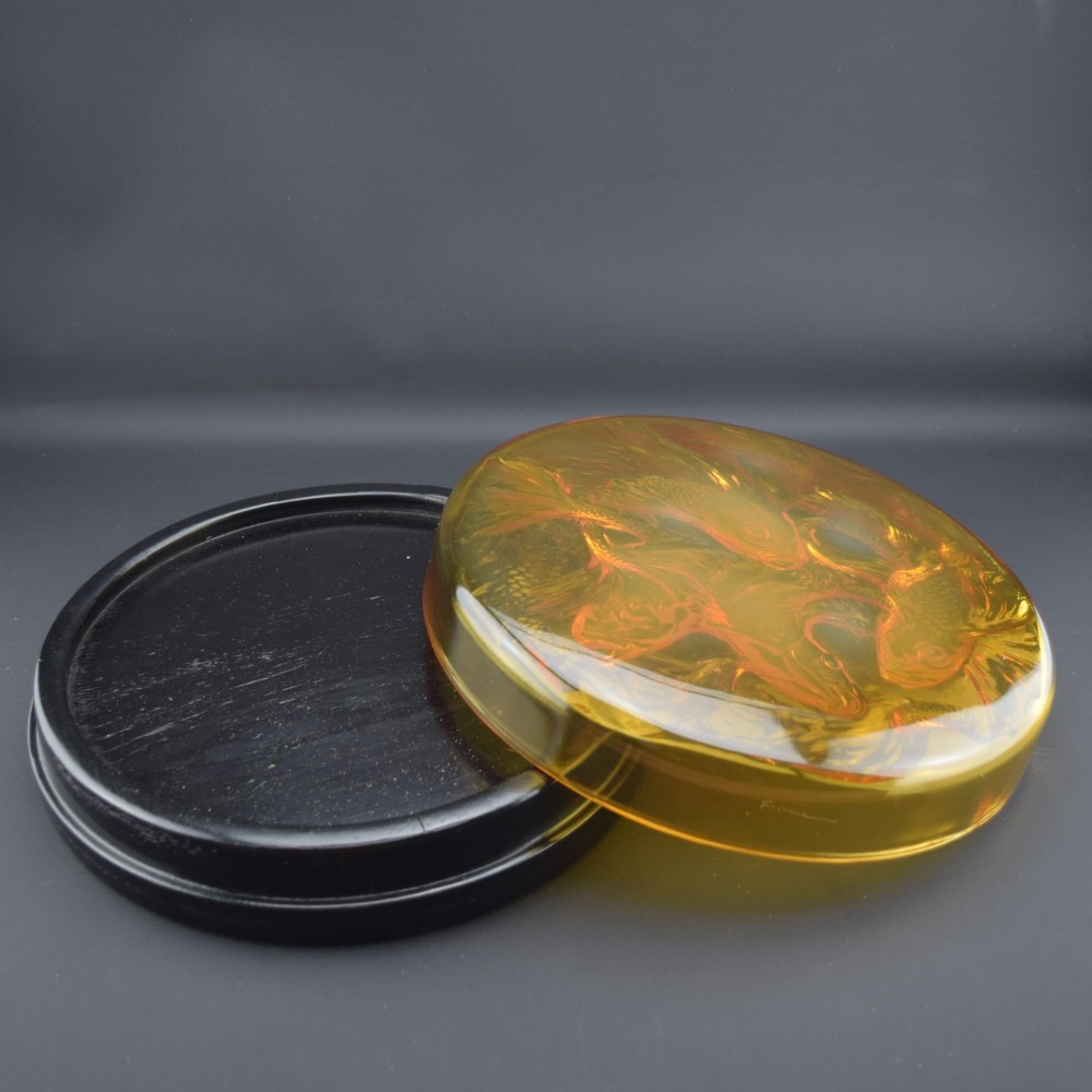 A circular amber opalescent glass box decorated with relief-moulded carp fish swirling in a central motif. View III