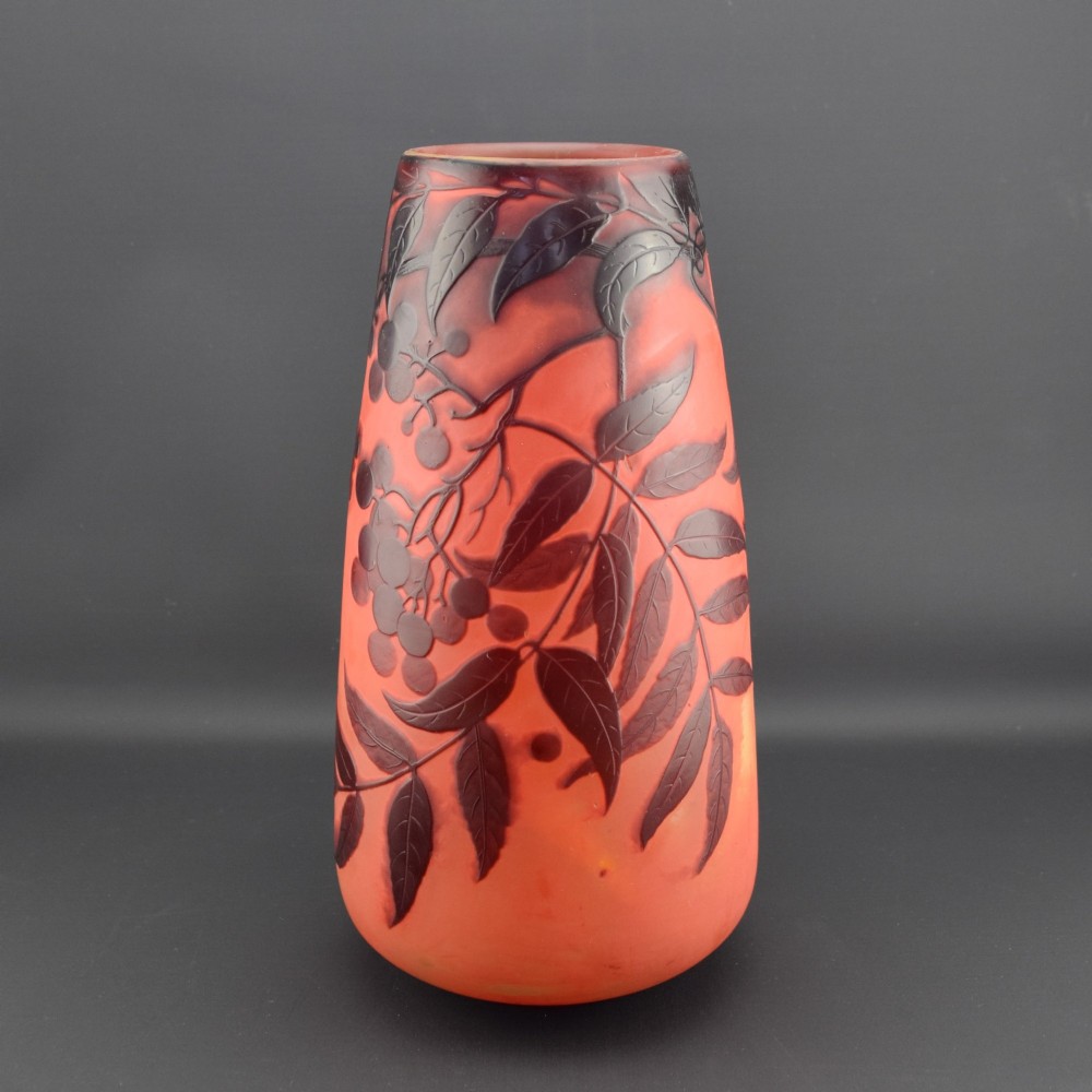 An Art Nouveau tapered cameo glass vase featuring a frosted coral orange ground with acid-etched dark red botanical leaf and berry motifs. View II