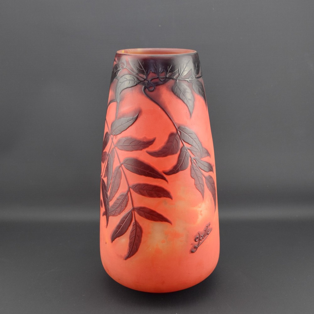 An Art Nouveau tapered cameo glass vase featuring a frosted coral orange ground with acid-etched dark red botanical leaf and berry motifs. View IV