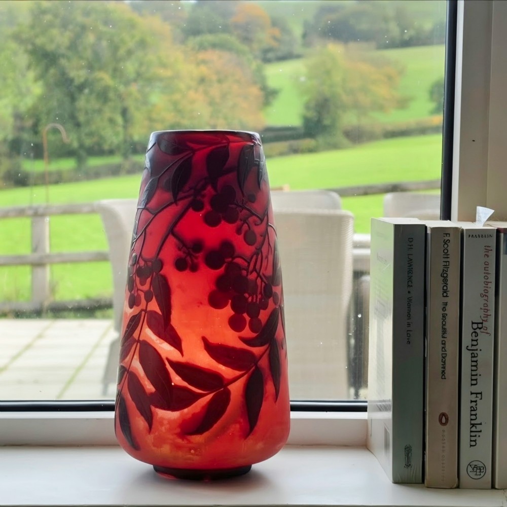 An Art Nouveau tapered cameo glass vase featuring a frosted coral orange ground with acid-etched dark red botanical leaf and berry motifs. View V