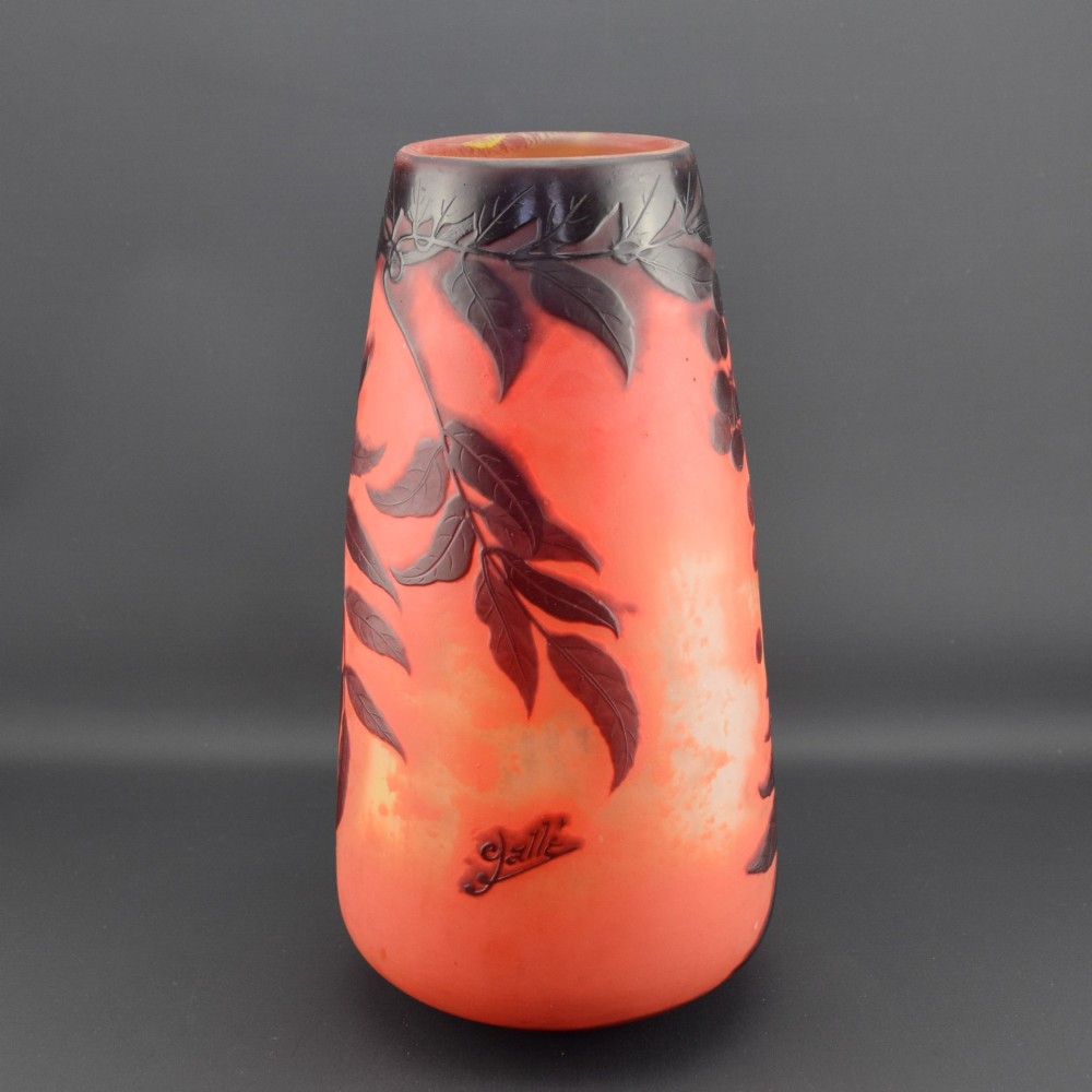An Art Nouveau tapered cameo glass vase featuring a frosted coral orange ground with acid-etched dark red botanical leaf and berry motifs. View VI