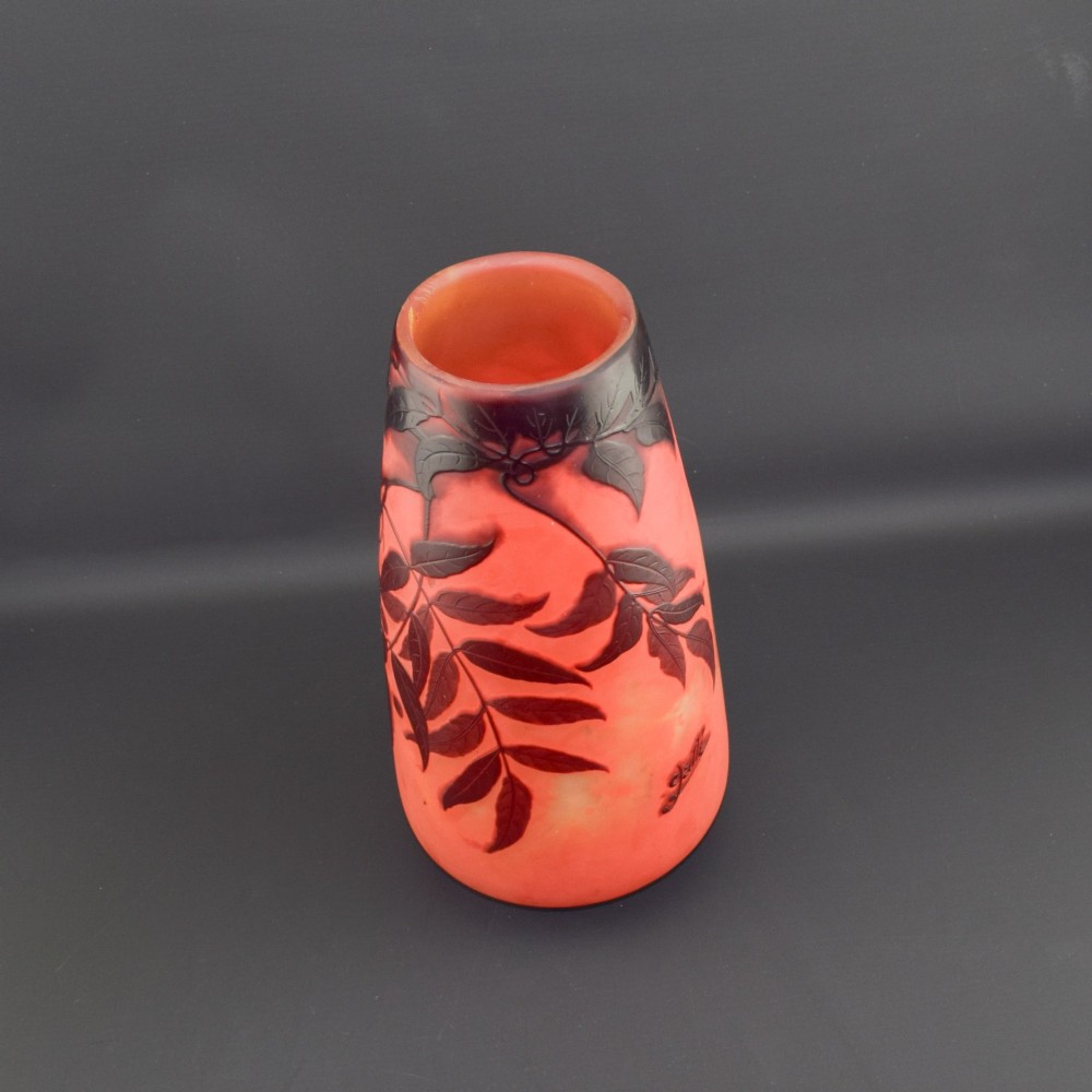 An Art Nouveau tapered cameo glass vase featuring a frosted coral orange ground with acid-etched dark red botanical leaf and berry motifs. View VII