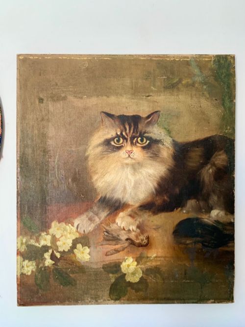 fig 1. A 19th-century naive school oil painting depicting a fluffy longhaired cat holding a small bird, set beside pale cream flowers against a warm brown background.