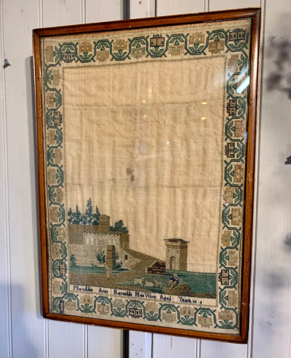 A framed early nineteenth-century needlework sampler featuring an embroidered architectural scene and floral border on a natural linen ground. View III