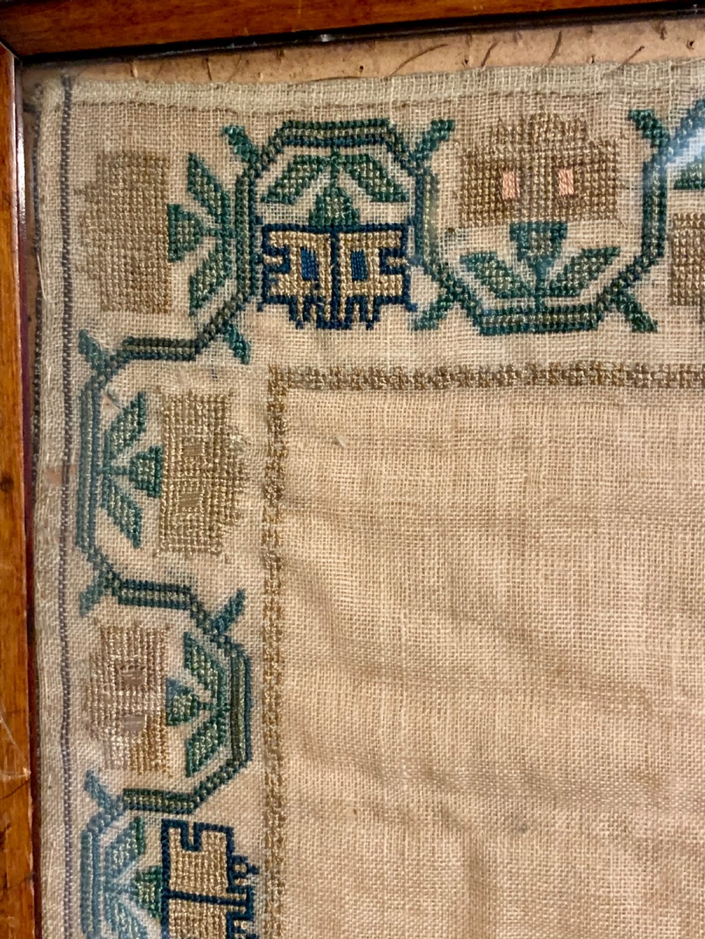 A framed early nineteenth-century needlework sampler featuring an embroidered architectural scene and floral border on a natural linen ground. View VIII