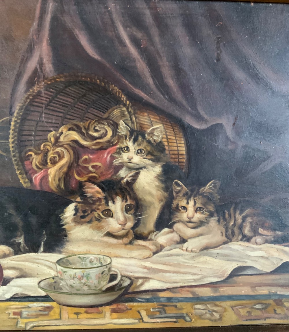 A 19th-century oil painting on board featuring a cat and three kittens beside a teacup, yarn balls, and a woven basket inside a wooden frame. View II