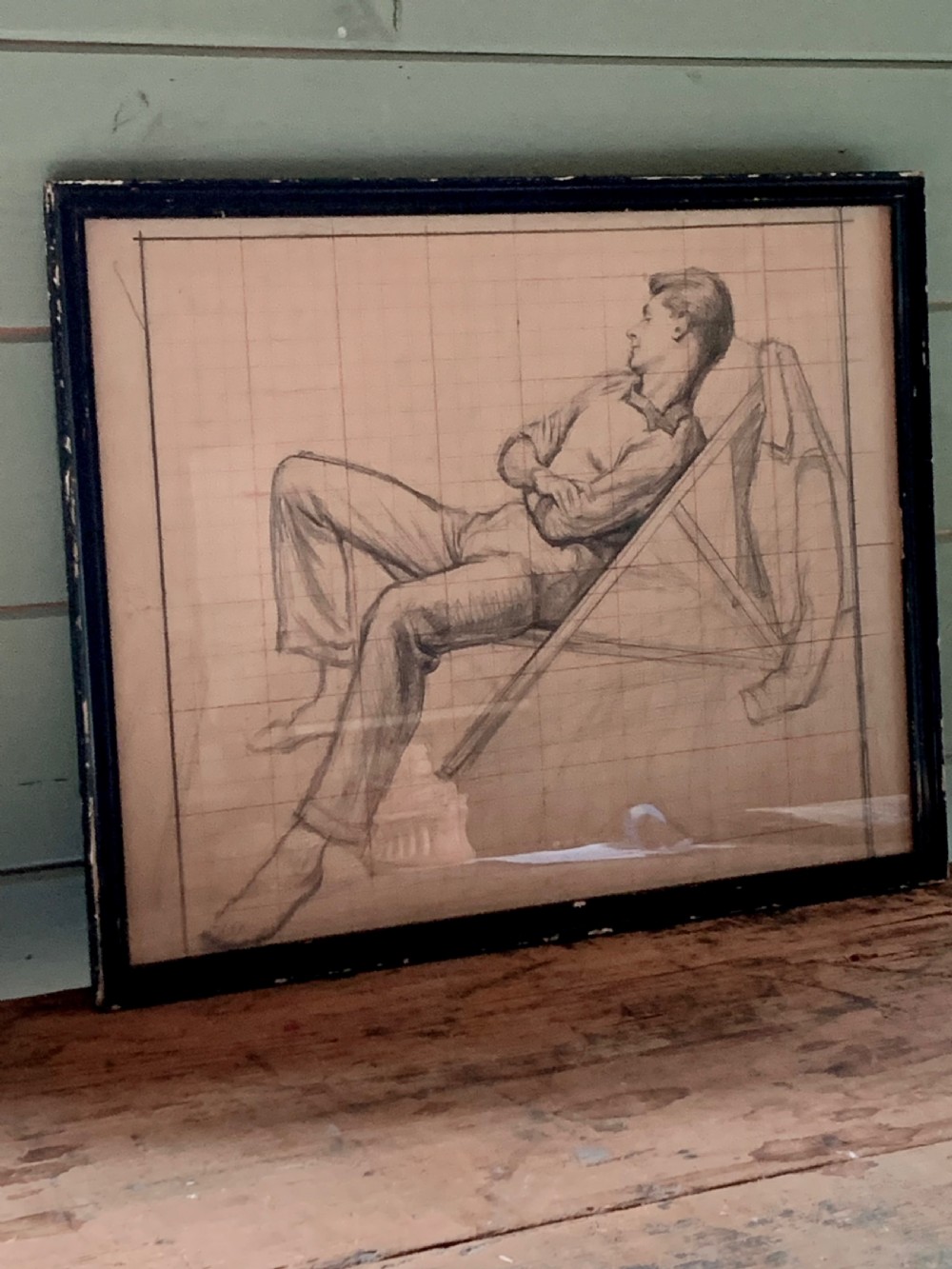 A framed monochrome pencil sketch on gridded paper showing a reclined male figure with arms crossed in a simple black frame. View IV