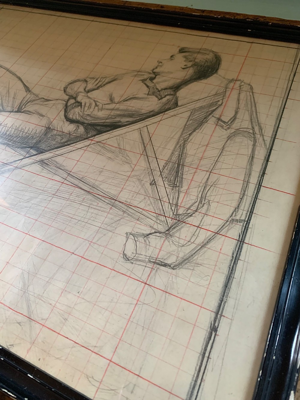 A framed monochrome pencil sketch on gridded paper showing a reclined male figure with arms crossed in a simple black frame. View VII