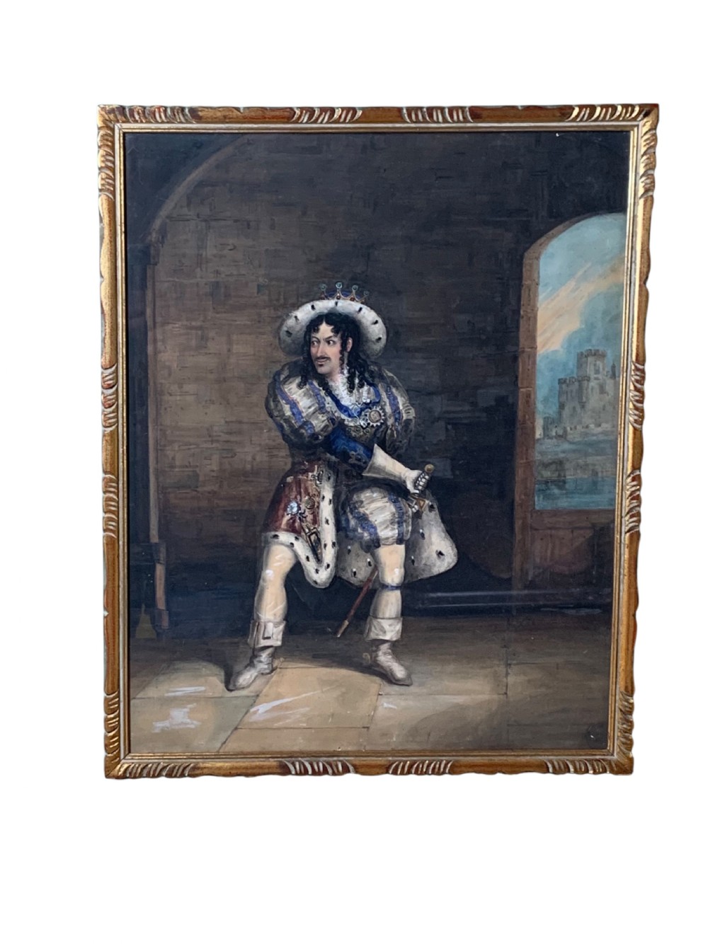 A framed watercolour portrait depicting a male figure in historical cavalier costume within a stone interior, encased in a gold moulded frame.