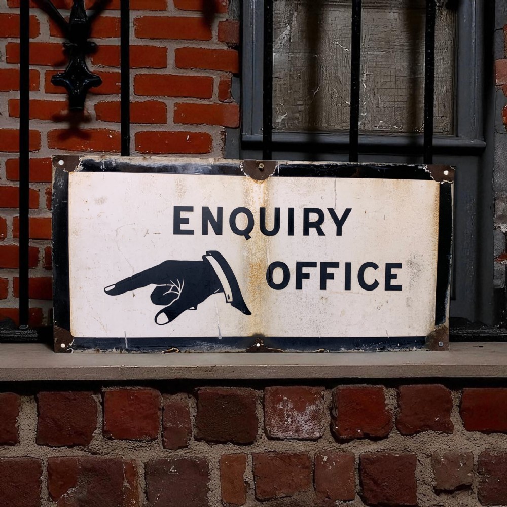 A rectangular off-white enamel sign displaying black block lettering reading ENQUIRY OFFICE alongside a pointing hand icon.