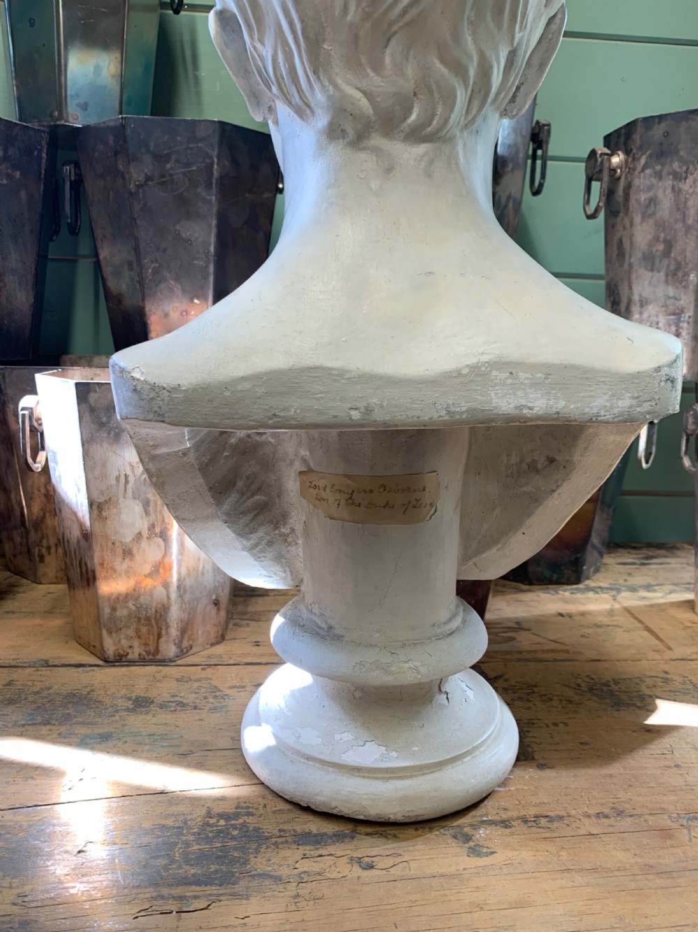 An off-white antique plaster bust depicting a young male on a circular moulded pedestal base. View VI